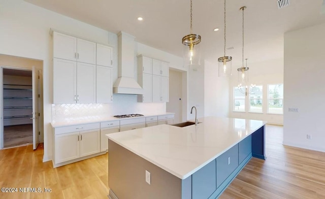 kitchen with a large island, white cabinets, and hanging light fixtures