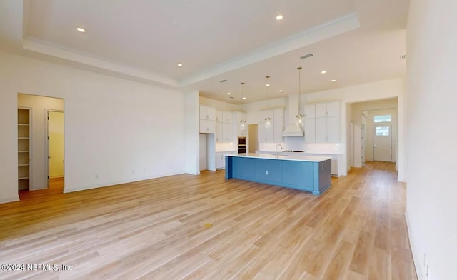 kitchen with a kitchen island with sink, light wood-type flooring, and white cabinetry