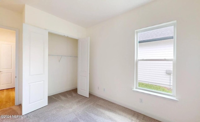 unfurnished bedroom with light carpet and a closet