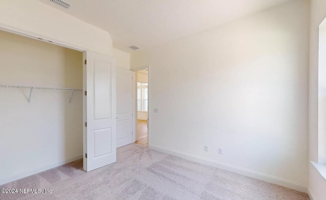 unfurnished bedroom with light carpet and a closet