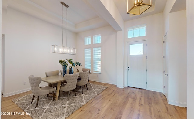 dining area with plenty of natural light, a high ceiling, and light hardwood / wood-style flooring