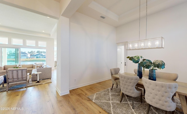 dining space featuring ornamental molding, light hardwood / wood-style floors, a high ceiling, and an inviting chandelier