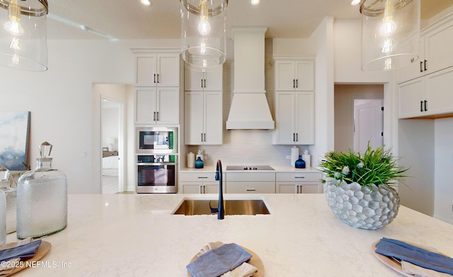 kitchen with backsplash, stainless steel oven, custom range hood, sink, and white cabinets