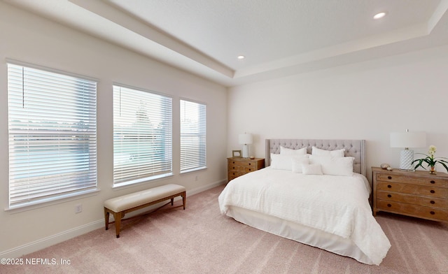 bedroom with light colored carpet and a tray ceiling