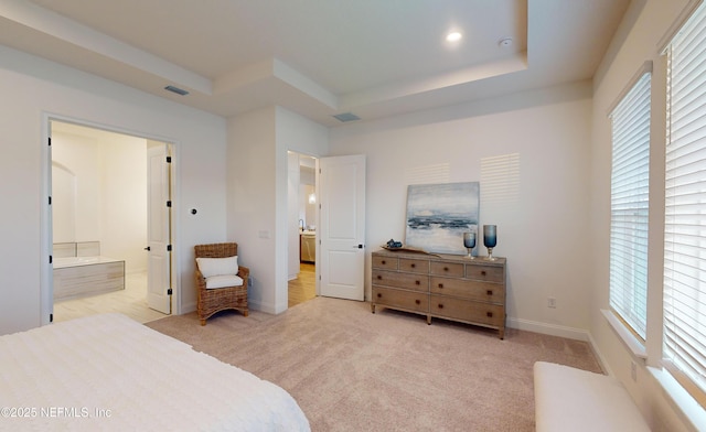 carpeted bedroom featuring connected bathroom and a tray ceiling