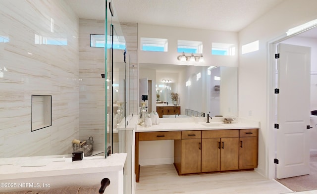 bathroom featuring tiled shower, a textured ceiling, and vanity