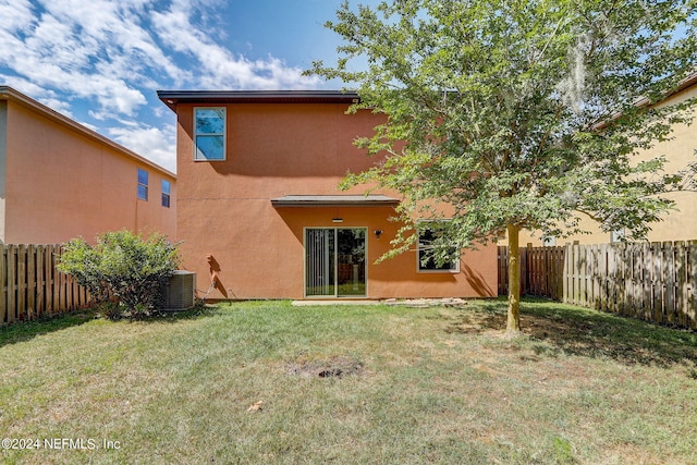 back of property featuring a yard and central AC