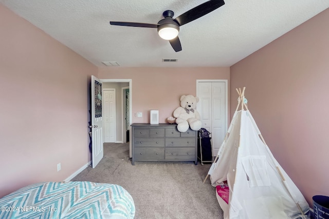 bedroom featuring a closet, a textured ceiling, ceiling fan, and light colored carpet