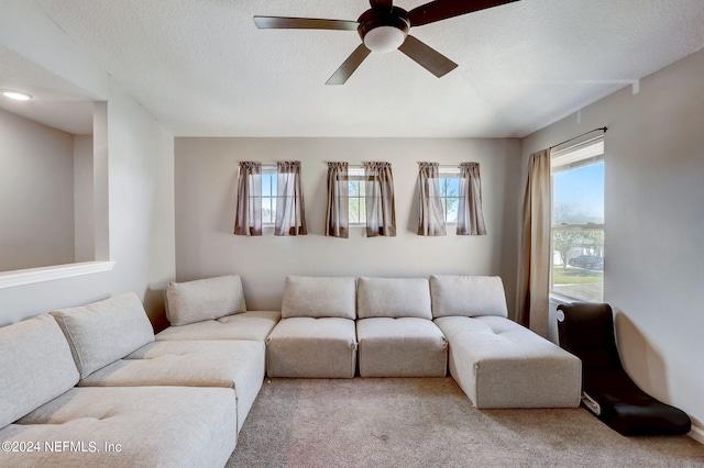 living room featuring ceiling fan, carpet floors, and a textured ceiling