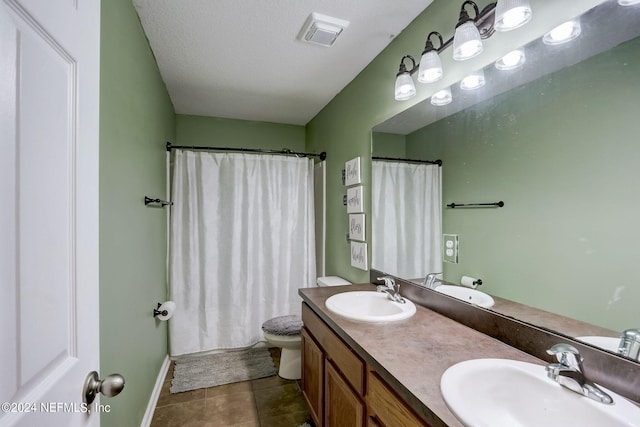 bathroom with double vanity, toilet, tile floors, and a textured ceiling