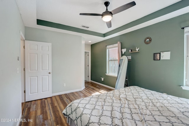 bedroom featuring ceiling fan, a tray ceiling, and hardwood / wood-style flooring