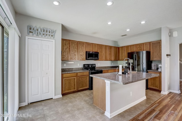 kitchen with appliances with stainless steel finishes, sink, a center island with sink, and light tile floors