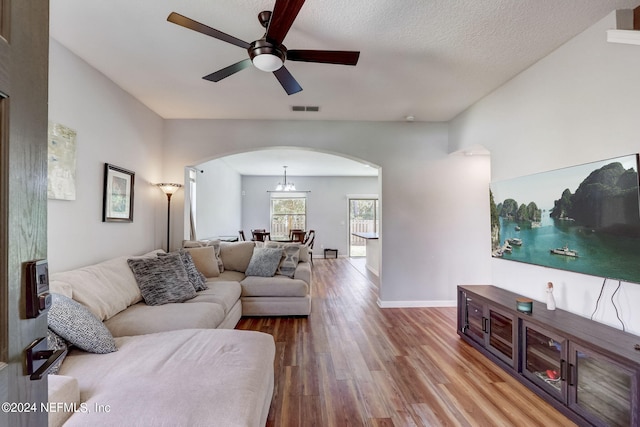 living room with wood-type flooring, ceiling fan, and a textured ceiling