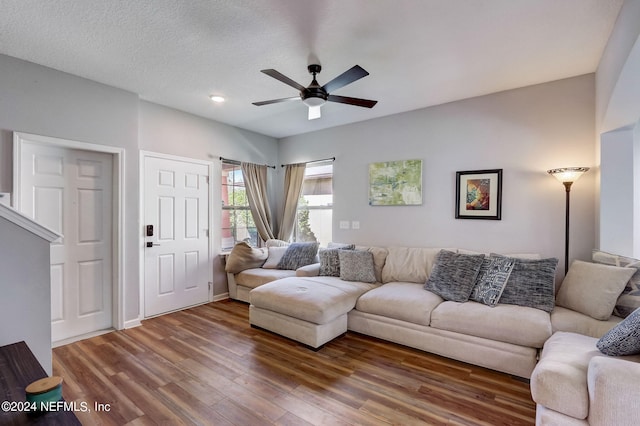 living room with dark hardwood / wood-style floors, ceiling fan, and a textured ceiling