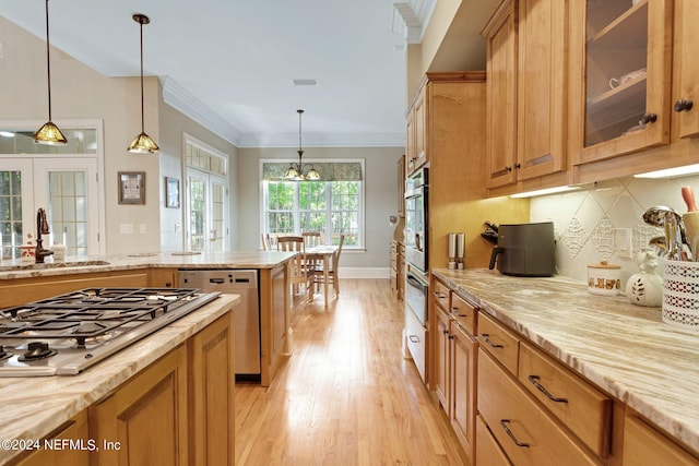 kitchen with sink, pendant lighting, backsplash, stainless steel appliances, and light wood-type flooring