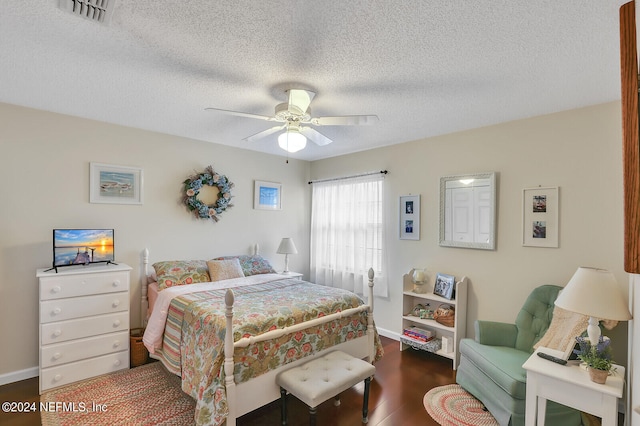 bedroom with ceiling fan, dark hardwood / wood-style flooring, and a textured ceiling