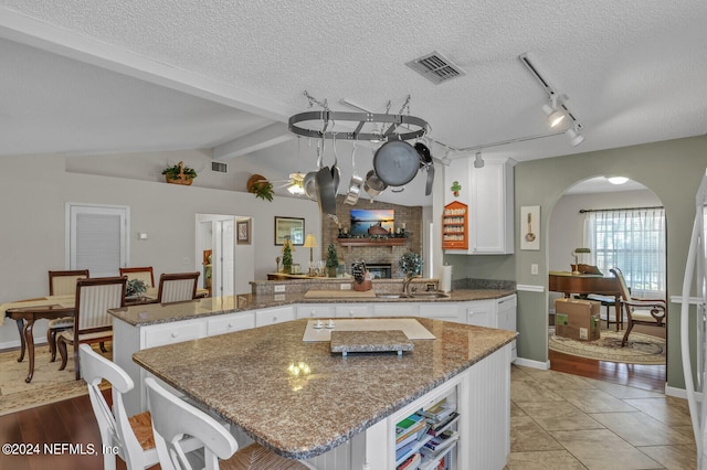 kitchen featuring kitchen peninsula, a brick fireplace, a textured ceiling, white cabinets, and a center island