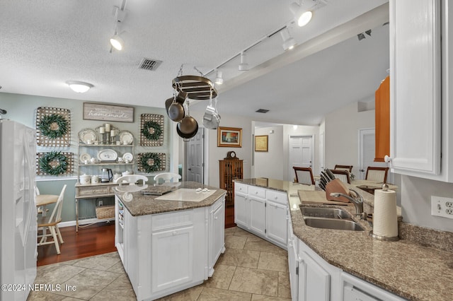 kitchen with white cabinetry, a center island, sink, stone countertops, and white appliances