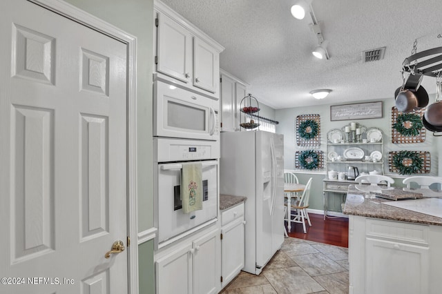 kitchen with white cabinets, white appliances, a textured ceiling, and rail lighting