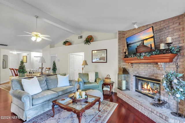 living room featuring vaulted ceiling with beams, ceiling fan, dark hardwood / wood-style flooring, and a brick fireplace