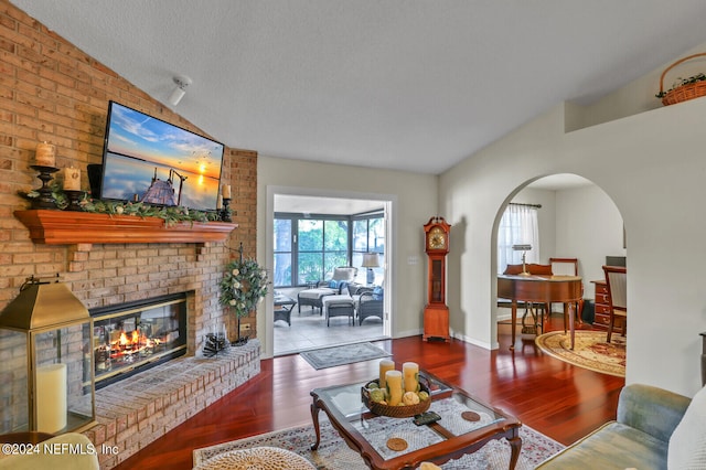 living room featuring a textured ceiling, a fireplace, vaulted ceiling, and hardwood / wood-style flooring