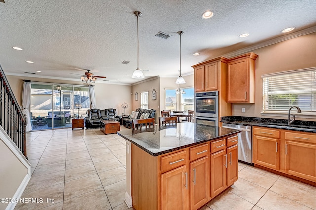 kitchen featuring ceiling fan, sink, stainless steel appliances, decorative light fixtures, and a center island