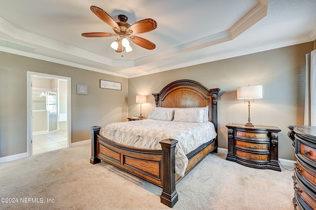 carpeted bedroom featuring a tray ceiling, ceiling fan, ensuite bathroom, and ornamental molding