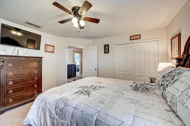 carpeted bedroom featuring a closet, a textured ceiling, and ceiling fan