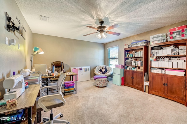 carpeted home office with ceiling fan and a textured ceiling