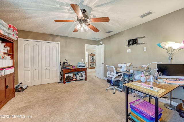 carpeted office space featuring ceiling fan and a textured ceiling