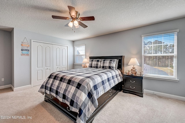 bedroom with light carpet, a closet, ceiling fan, and a textured ceiling