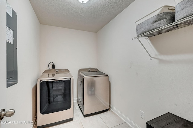 laundry room with light tile floors, washer and clothes dryer, and a textured ceiling