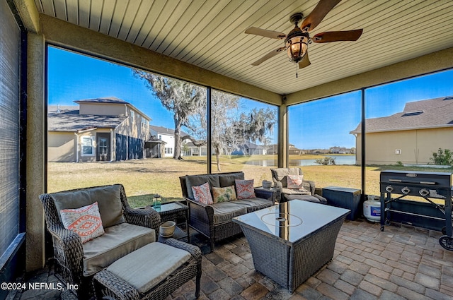 sunroom featuring a water view and ceiling fan