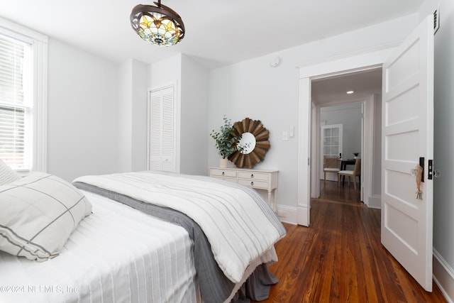 bedroom with dark hardwood / wood-style floors, an inviting chandelier, and a closet