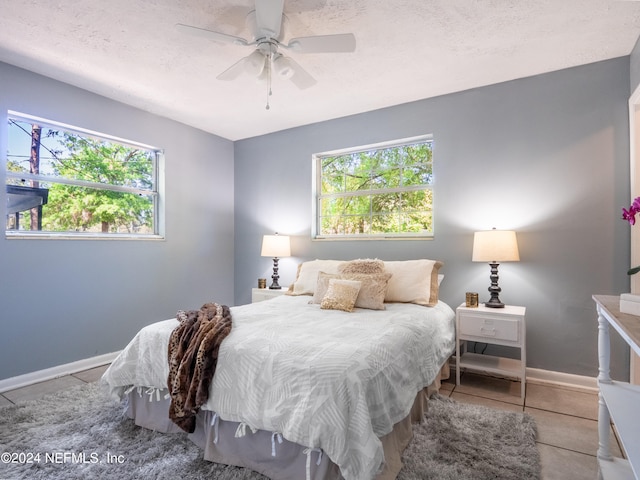 bedroom with ceiling fan, light tile patterned flooring, and a textured ceiling