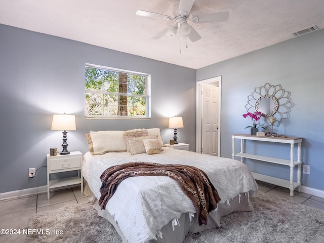 bedroom featuring a textured ceiling, ceiling fan, and light tile patterned floors