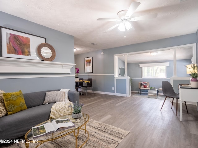 living room with ceiling fan, light hardwood / wood-style flooring, and a textured ceiling