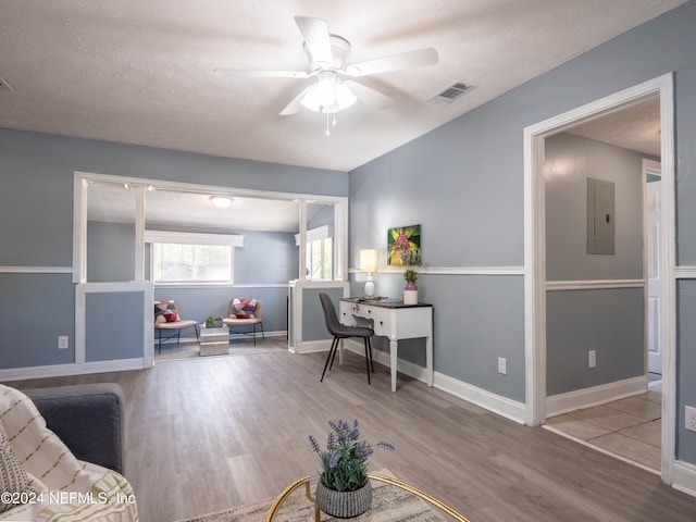 office area featuring a textured ceiling, ceiling fan, light hardwood / wood-style floors, and electric panel