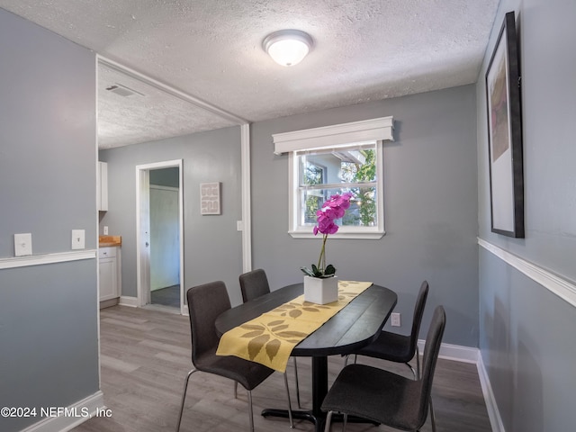 dining area featuring a textured ceiling and light hardwood / wood-style floors