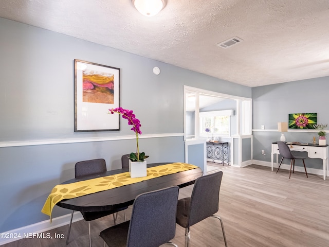 dining space with a textured ceiling and light wood-type flooring