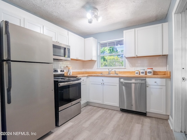 kitchen featuring appliances with stainless steel finishes, light hardwood / wood-style flooring, and white cabinetry