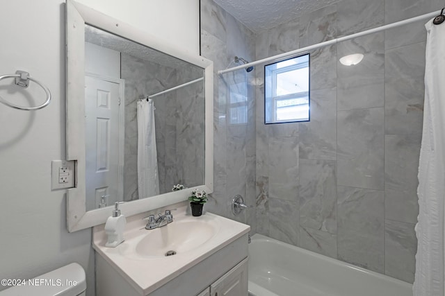 full bathroom featuring toilet, vanity, a textured ceiling, and shower / bathtub combination with curtain