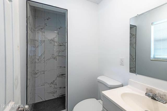 bathroom featuring a tile shower, vanity, and toilet