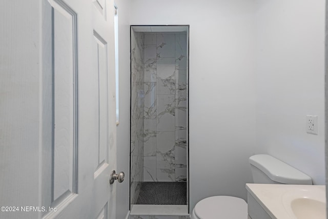 bathroom featuring a tile shower, vanity, and toilet