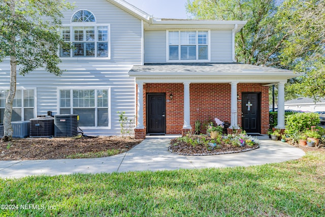 view of front of house featuring cooling unit, a front lawn, and a porch