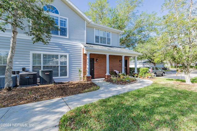 view of front of house with central AC unit, a front yard, and covered porch