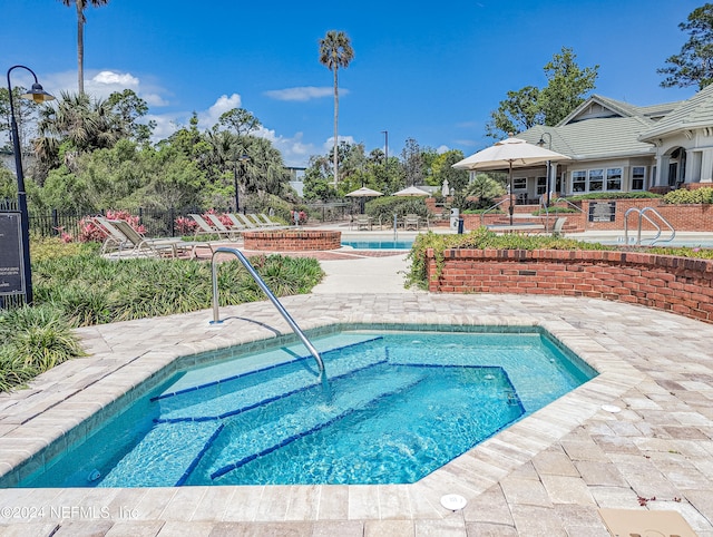 view of swimming pool featuring a hot tub and a patio area