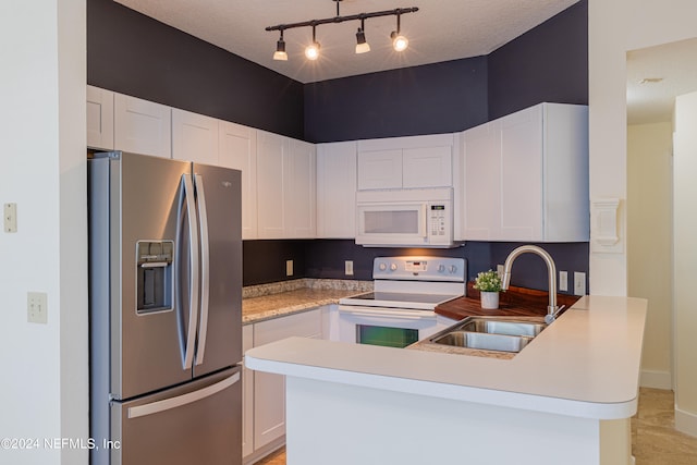 kitchen featuring rail lighting, white cabinets, white appliances, decorative light fixtures, and sink