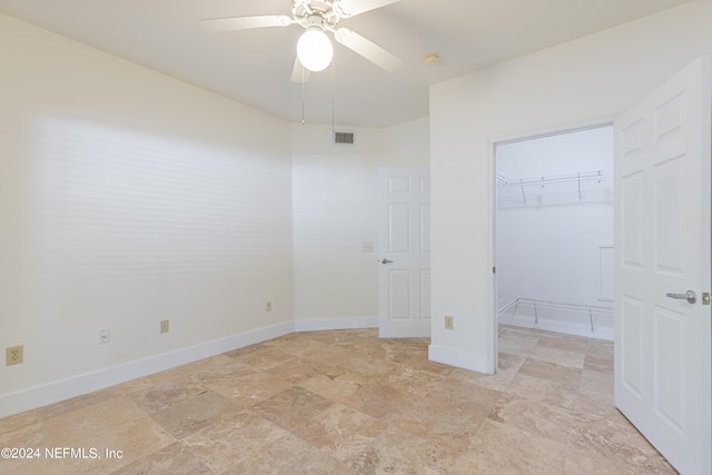 unfurnished bedroom featuring a spacious closet, a closet, and ceiling fan