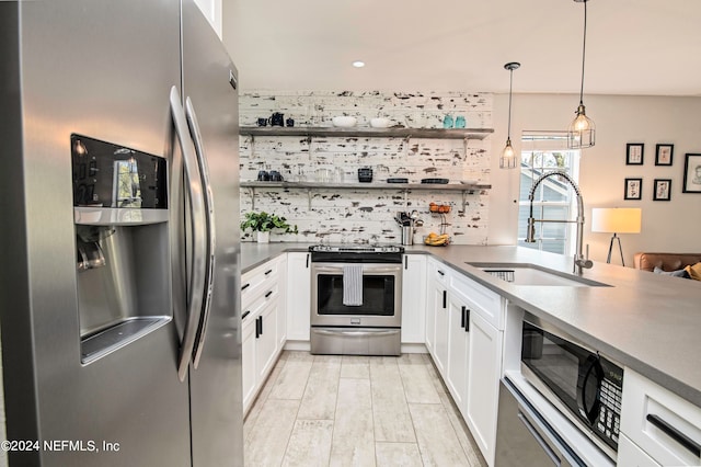 kitchen featuring appliances with stainless steel finishes, decorative light fixtures, sink, kitchen peninsula, and white cabinetry